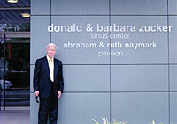 Photo of Abraham Naymark standing in front of the building that bears the names of him and his wife. Photo of Abraham Naymark standing in front of the building that bears the names of him and his wife.